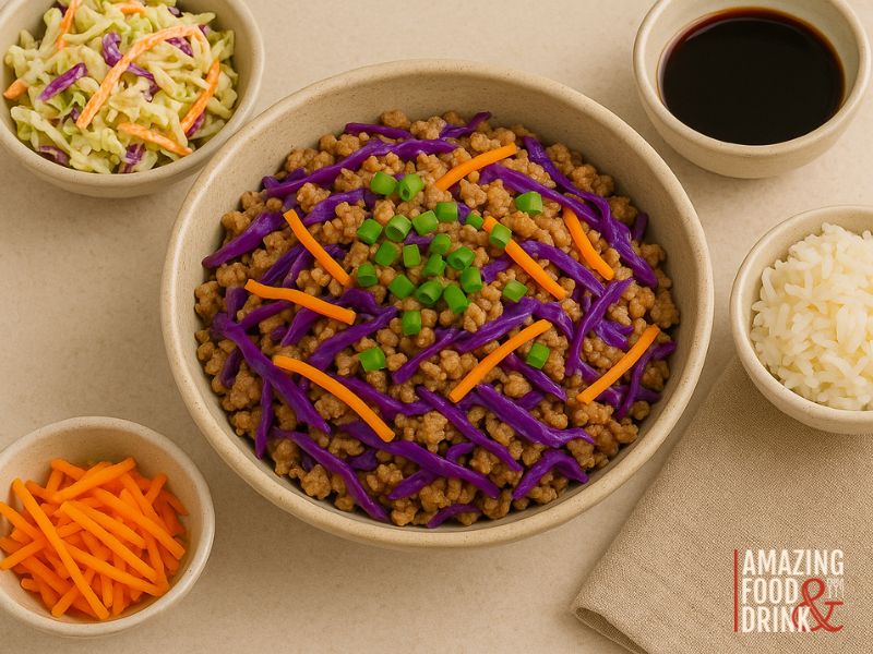 A bowl of ground meat topped with shredded purple cabbage, carrots, and green onions, surrounded by bowls of coleslaw, rice, carrots, and soy sauce&mdash;this dish is a tasty egg roll in a bowl inspired by classic Chinese-American flavors.