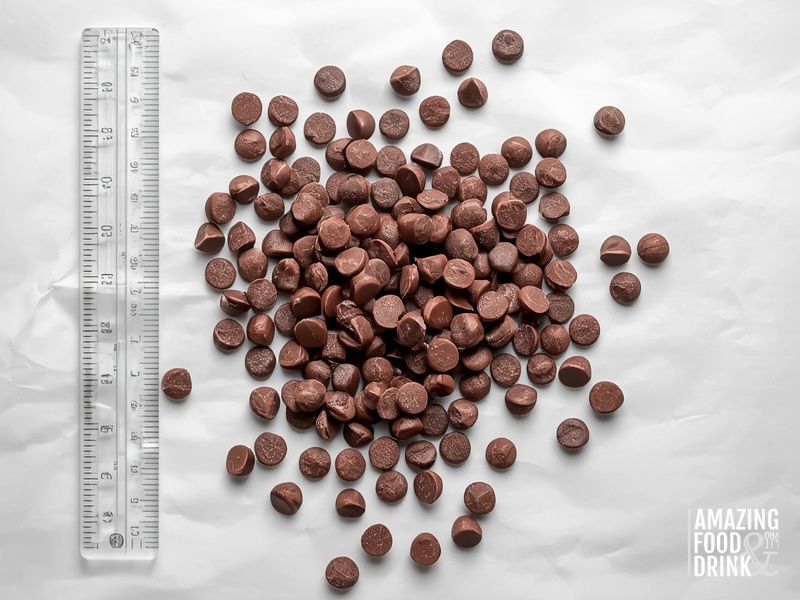 Uniform homemade dairy-free chocolate chips on parchment paper with ruler showing size scale