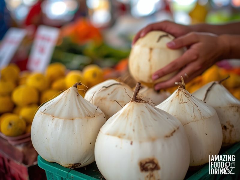 Fresh young white coconuts displayed at Asian market showing cone-shaped tops and pale exterior